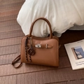 Sac à main style Kelly en cuir marron avec boucle métallique et bandoulière sur bois - Brun Avec Pendentif Bretzel Boulier