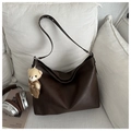 Detalle de bolso tote de cuero marrón oscuro con un osito de peluche en entorno acogedor - Café con Colgante