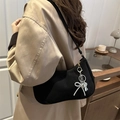 Chic black chain shoulder bag with silver bow charm worn by a model in a beige blazer - With Charm / Black