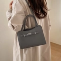 Elegant dark grey minimalist leather handbag with silver lock shown on a model - No Pendant / Gray