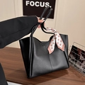 Bolso tote grande de cuero negro con pañuelo rosa de lunares sobre mesa de madera - Negro