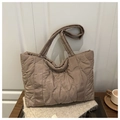 Detail der gesteppten Puffer-Tasche in Dunkelkhaki auf einem Holztisch platziert - Khaki