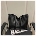 Close-up of a large black tote bag placed on a chair with magazine prop details - Black