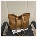 Detail view of a brown faux leather tote bag with vertical stitching on a black chair - Brown