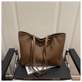 Detailed view of the brown leather tote bag texture on a modern leather chair - Coffee