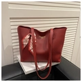 Detail view of red leather tote bag featuring golden lettering and geometric silk scarf - Red