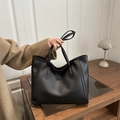 Klassische schwarze Tragetasche aus Kunstleder getragen von einem Modell im beigen Mantel - Schwarz
