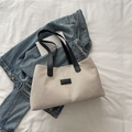 Minimalistische beige gewebte Tragetasche mit schwarzen Griffen auf weißem Stoff - Schwarz