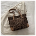 Detail view of leopard print tote bag featuring brown leather trim and metal accent - Brown