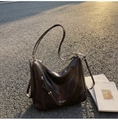 Detail view of large brown hobo bag featuring side zipper and brand text on leather - Coffee