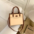 Retro-Handtasche in Beige und Braun auf einem gemütlichen weißen Stoffsofa - Khaki