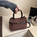 Brown frosted suede handbag with leather trim and gold hardware in a lifestyle setting - Brown