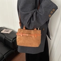 Brown suede crossbody bag with vintage gold buckle shown on grey coat model - Brown