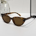Occhiali da sole cat-eye tartarugati con lenti marroni su superficie bianca pulita - Montatura Leopardata / Lenti Tè