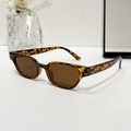 Retro narrow oval sunglasses with tortoise shell frame and brown lenses in a lifestyle setting - Leopard Frame / Tea Lens