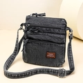 Detail of gray washed denim crossbody bag with three zipper layers and leather tag - Black