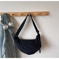 Detail of minimalist black nylon crescent bag hanging on a hook with casual outfit - Black