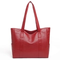Dettaglio della grande borsa tote rossa con texture martellata e spallacci rinforzati - Rosso