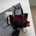 Borsa bicolore bordeaux e nero con ciondolo a nappa posata su abito grigio - Rosso Vino Con Pendente