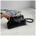 Detailed view of a vintage black shell bag with gold metal frame and ball clasp on fabric - Black