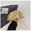 Dettaglio di una pochette da sera dorata con pieghe ondulate e sottile catena in metallo - Oro