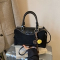 Chic black handbag with bow detail and pom-pom charm on a silver suitcase - Black With Pendant