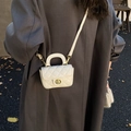 Mini cream quilted crossbody bag with gold buckle and chain strap shown on a model - White