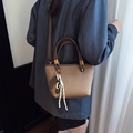 Brown leather handbag with chocolate charm and woven rope shown as a crossbody bag - Apricot