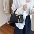 Borsa a mano retrò nera con chiusura dorata e ciondolo indossata da una modella - Nero