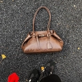 Retro deep brown underarm bag with vintage texture and buckle on asphalt ground - Brown