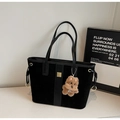 Detail of black suede tote bag with leather strap, gold buckle, and teddy bear charm - Black