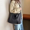 Detail view of large black canvas tote bag with top handles and shoulder strap on a model - Black