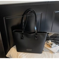 Gros plan sur un grand sac cabas noir avec texture grainée et détail logo métallique - Noir sans Pendentif