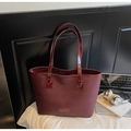 Gros plan du sac cabas en cuir saffiano bordeaux avec plaque logo et accessoires de bureau - Rouge Vin Sans Pendentif
