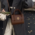 Vintage brown leather shoulder bag with gold metal clasp shown in autumn street style - Brown