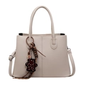 Elegant beige tote bag with litchi texture leather and leopard bear charm on white background - Off White