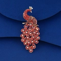 Détail de la broche paon avec strass rouges et base dorée sur fond bleu texturé - Paon Doré Strass Couleur Rubis (XD824397-4)