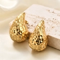 Detail of gold teardrop earrings with hammered texture on a neutral stone background - Hammered Teardrop Gold