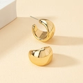 Macro shot of chunky gold-plated teardrop earrings with a polished mirror finish - C-Type Gold