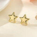 Detailed close-up of polished gold star earrings on a minimalist cream aesthetic surface - Star Gold