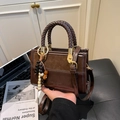 Dark brown textured handbag with woven handles and colorful bead charm in crossbody style - Brown