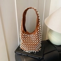 Brown matte leather hobo bag with white pearl studs on a black book background - Brown