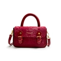 Red crossbody bag with snakeskin print flap and vintage gold buckles on white background - Red