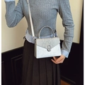 Detail of silver grey snake pattern handbag with round metal clasp and cross-body strap - White