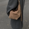 Bolso hobo grande de ante marrón con correa ajustable de ojales llevado por una modelo - Caqui