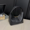 Detail einer schwarzen Ledertasche mit zwei goldenen Reißverschlüssen und Logo-Prägung - Schwarz