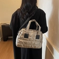 Gewatteerde goudkleurige tote bag met zwarte riem, gedragen door een vrouwelijk model - Goud