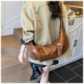 Detaillierte Textur der dunkelbraunen Falten-Hörnchen-Tasche aus glänzendem Leder - Braun
