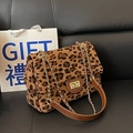 Chic leopard print crossbody bag with gold rotating lock and chain strap on dark background - Brown