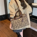 Leopard print tote bag with brown leather handles and wide shoulder strap in home setting - Black Grid